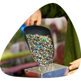 Close up of plastic granulate being placed into a machine in a plastic waste recycling plant